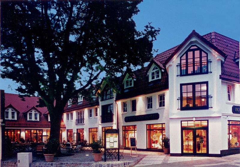 ein großes weißes Gebäude mit einem Baum davor in der Unterkunft Romantik Hotel Kaufmannshof in Bergen auf Rügen