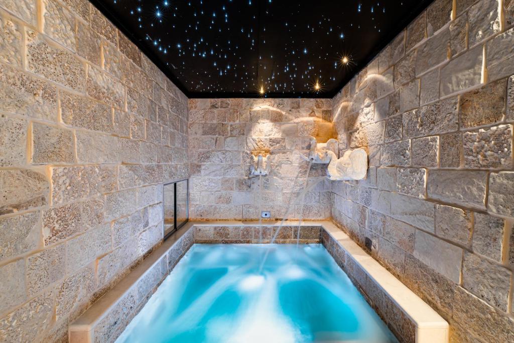une baignoire jacuzzi dans une salle de bains aux murs de pierre dans l'établissement Fountain - Suite Santeramo, à Santeramo in Colle