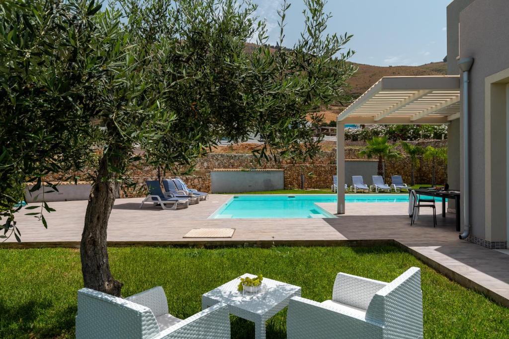 einen Hinterhof mit einem Pool mit Stühlen und einem Tisch in der Unterkunft Nuova Villa a Scopello con piscina privata in Balata di Baida
