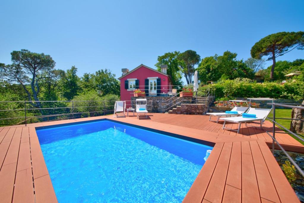 a swimming pool with a deck and a house at I Giardini di Camogli - VILLA SÀRVIA, garden&pool in Camogli