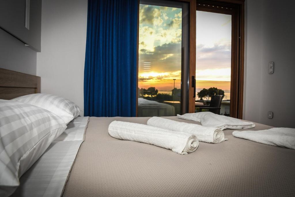 a bed with towels on it in front of a window at Seaside Luxury Apartments Kremasti in Kremasti