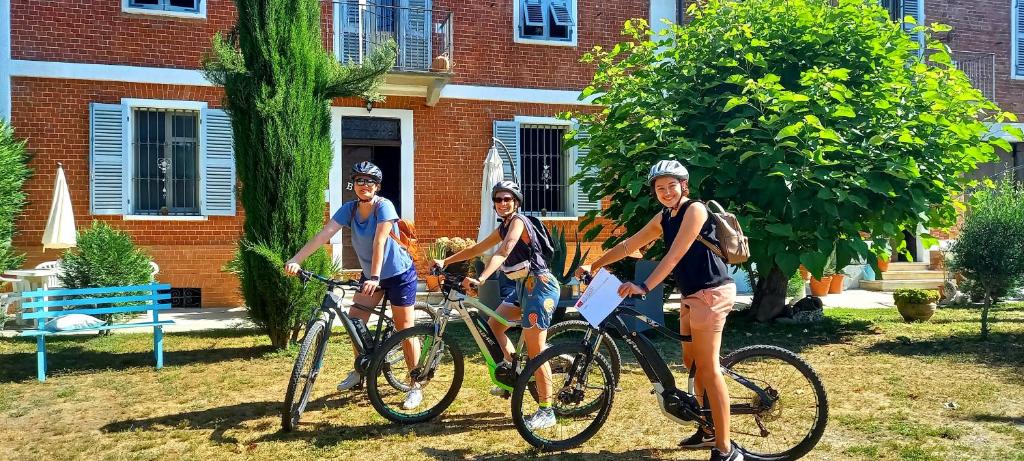tre uomini in bicicletta davanti a un edificio di Bed & Tours Dimora di campagna a Castelnuovo Belbo