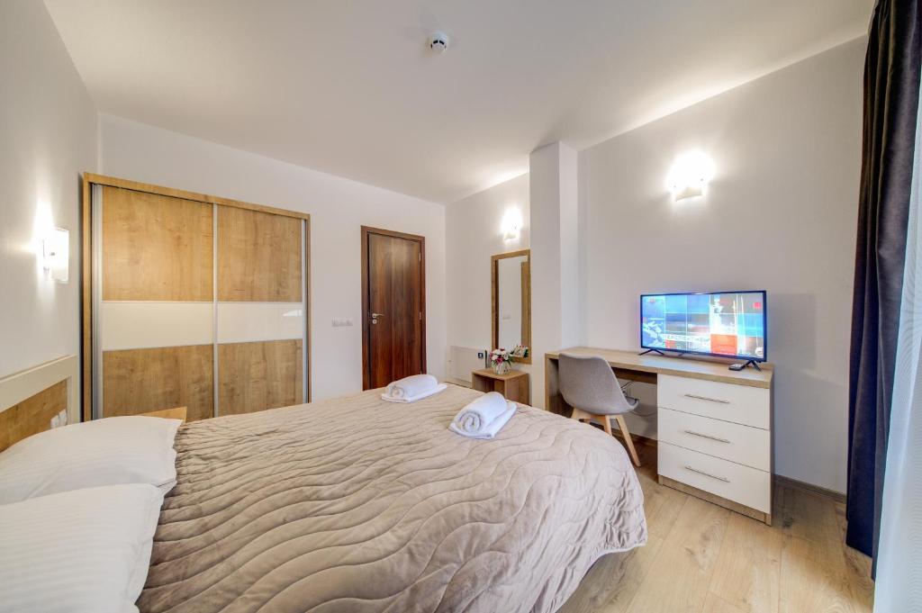 a bedroom with a bed and a desk and a television at Smolyan Lakes Apartment / Апартамент Смолянски езера in Smolyan