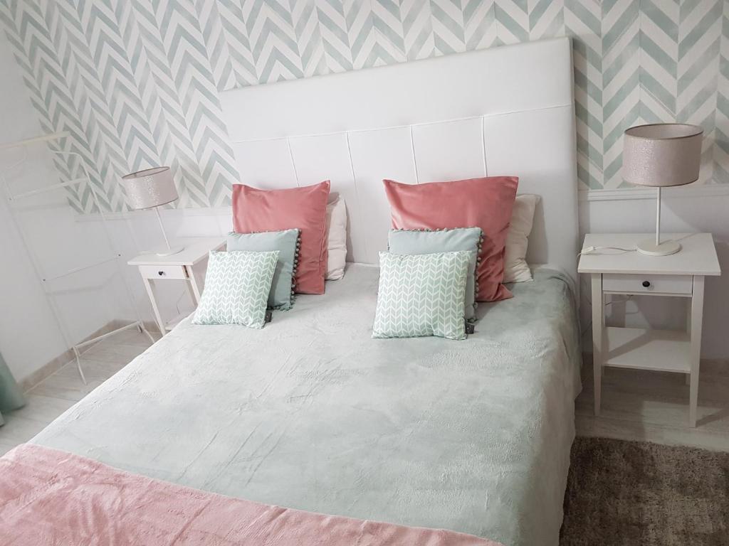 1 dormitorio con 1 cama grande con almohadas rosas y azules en Apartamento Alagoinha by Umbral, en Vila Nova de Milfontes