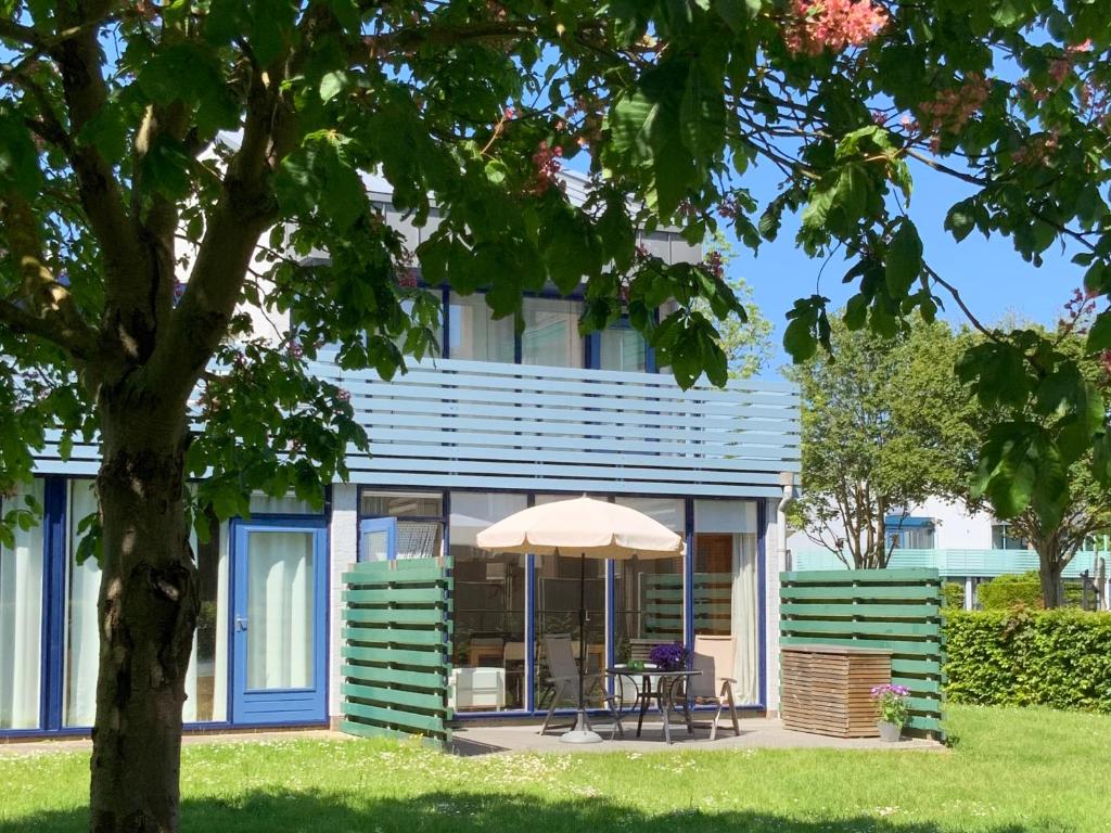 a house with a table and an umbrella in front of it at The Green Studio, Lopinge 94 in Cadzand
