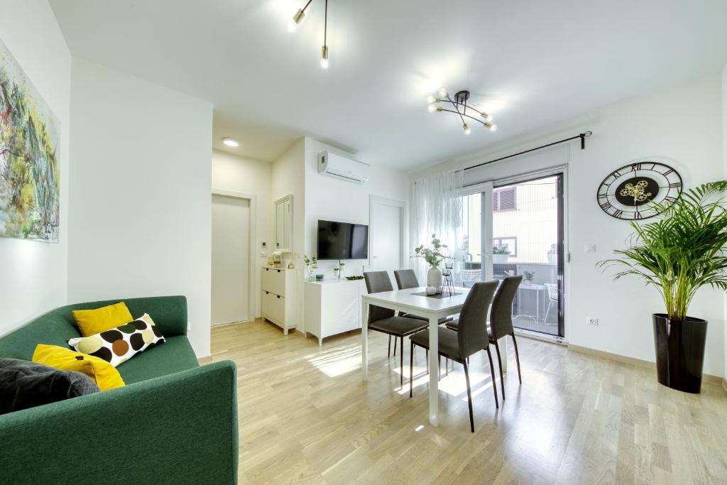Una sala de estar con un sofá verde y una mesa. en Apartment Alegria Zadar, en Zadar