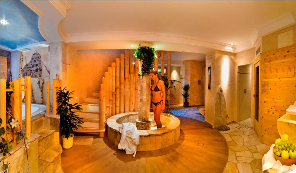 a woman is standing next to a tree in a room at Naturhotel Sonnenhof in Chiusa