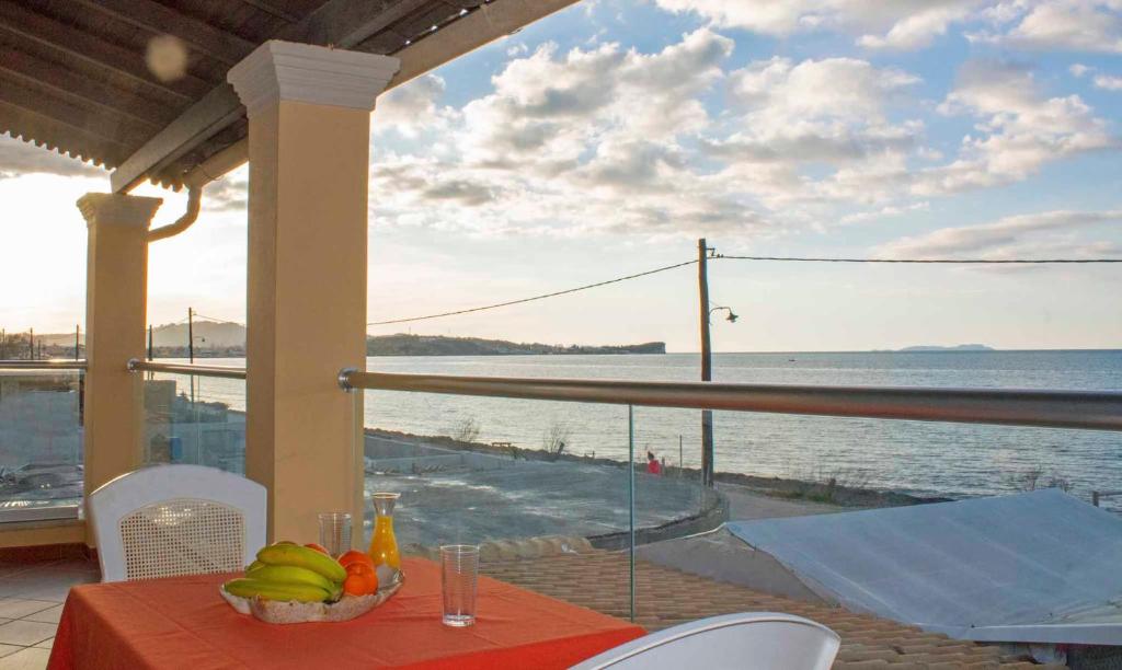 a table with a bowl of fruit on a balcony at Frosos Beachfront Maisonette Acharavi in Acharavi