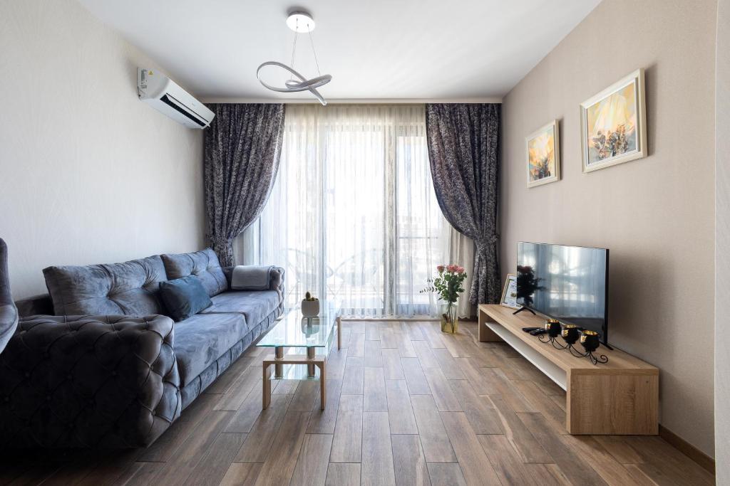 ein Wohnzimmer mit einem blauen Sofa und einem TV in der Unterkunft Helena Holiday B in Sweti Konstantin