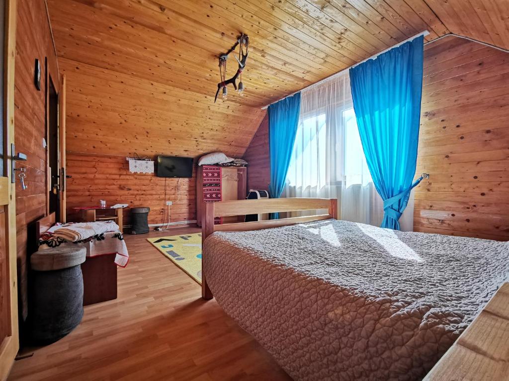 a bedroom with a bed and a blue curtain at Jugul Țăranului Agropensiune Polovragi, Gorj in Polovragi