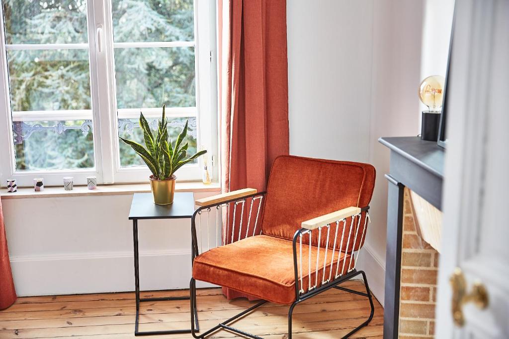 a chair and a table in a room with a window at Demeure de Manneville - SPA - 1Km des plages de Cabourg in Dives-sur-Mer