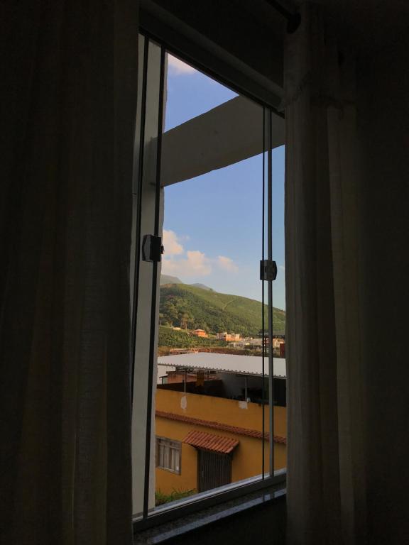 ein offenes Fenster mit Blick auf ein Gebäude in der Unterkunft apartamento fruto da terra 302 VISTA LATERAL MONTANHAS in Caparaó Velho