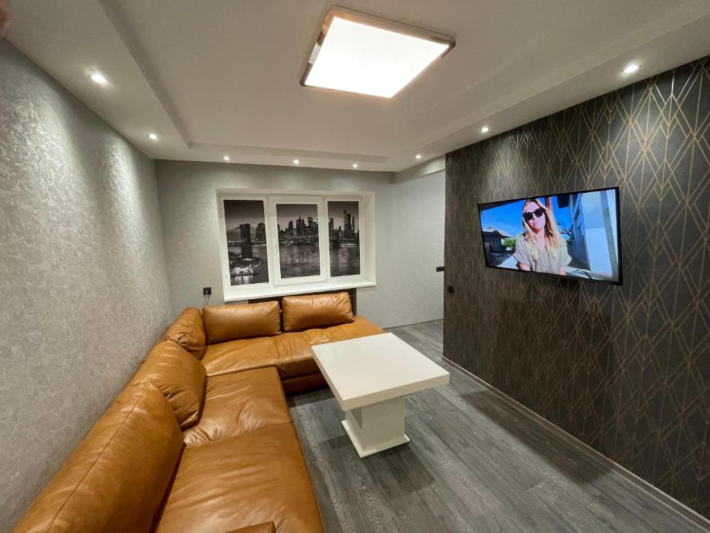 a living room with a couch and a tv on a wall at Elite Apartments in Rēzekne