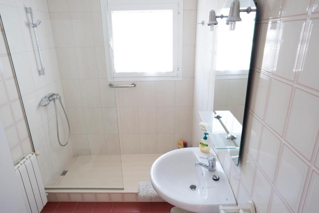 a white bathroom with a sink and a shower at Orquideas in Cala Galdana