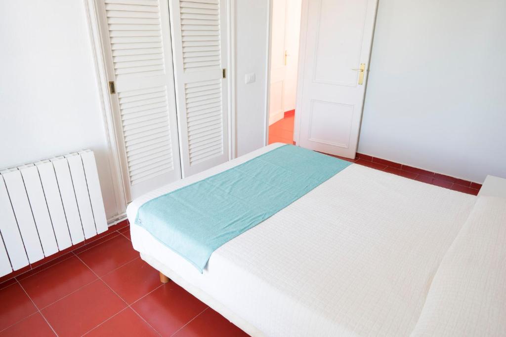 a white bed in a room with a red floor at Orquideas in Cala Galdana