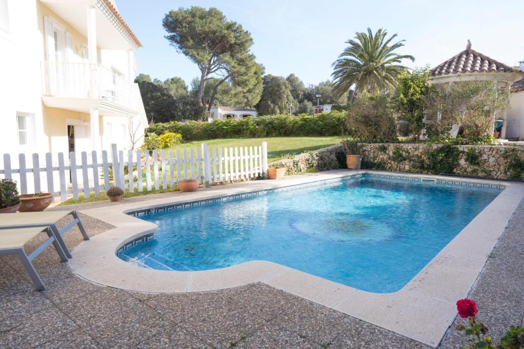una piscina en un patio con una valla blanca en Orquideas, en Cala Galdana