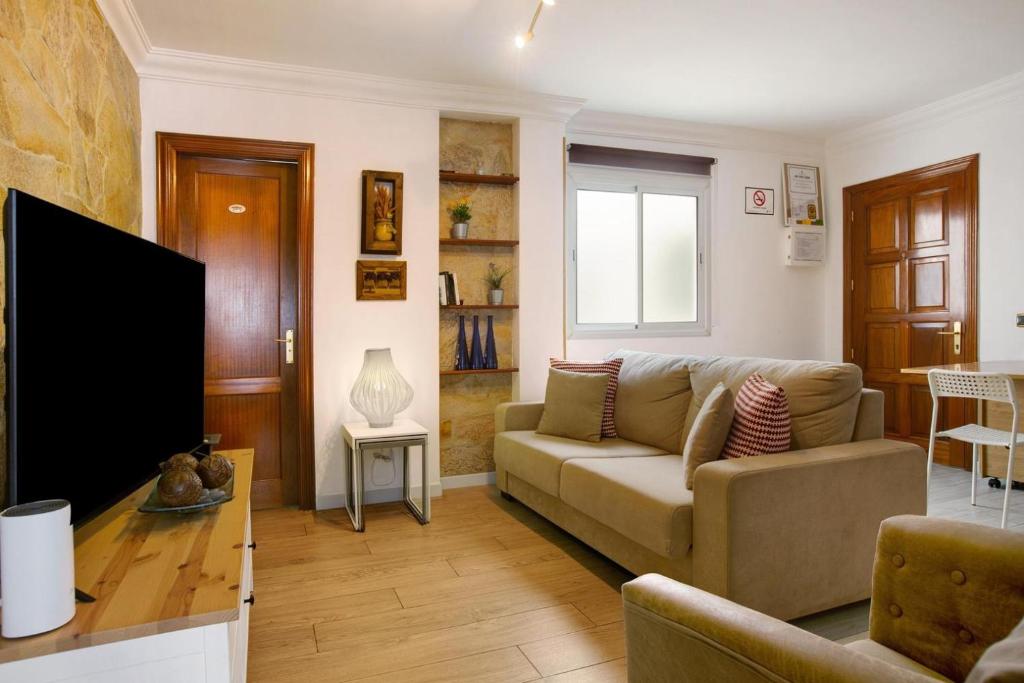 Una sala de estar con un sofá y un televisor. en Magara Suite Las Canteras, en Las Palmas de Gran Canaria