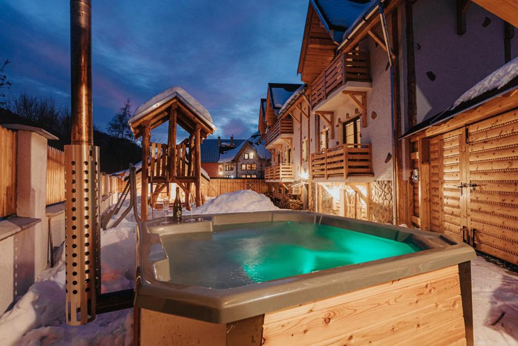 una bañera de hidromasaje en un patio cubierto de nieve con una casa en Penzión Natália en Terchová