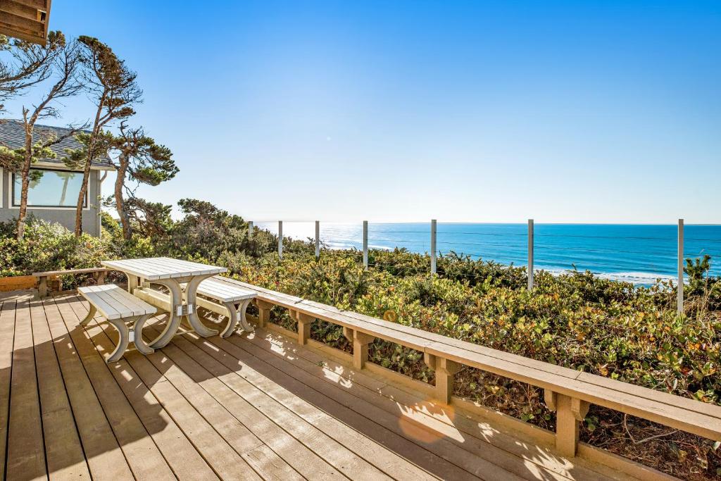 a wooden deck with a table and bench overlooking the ocean at Cape Kuh'lye in Lincoln City