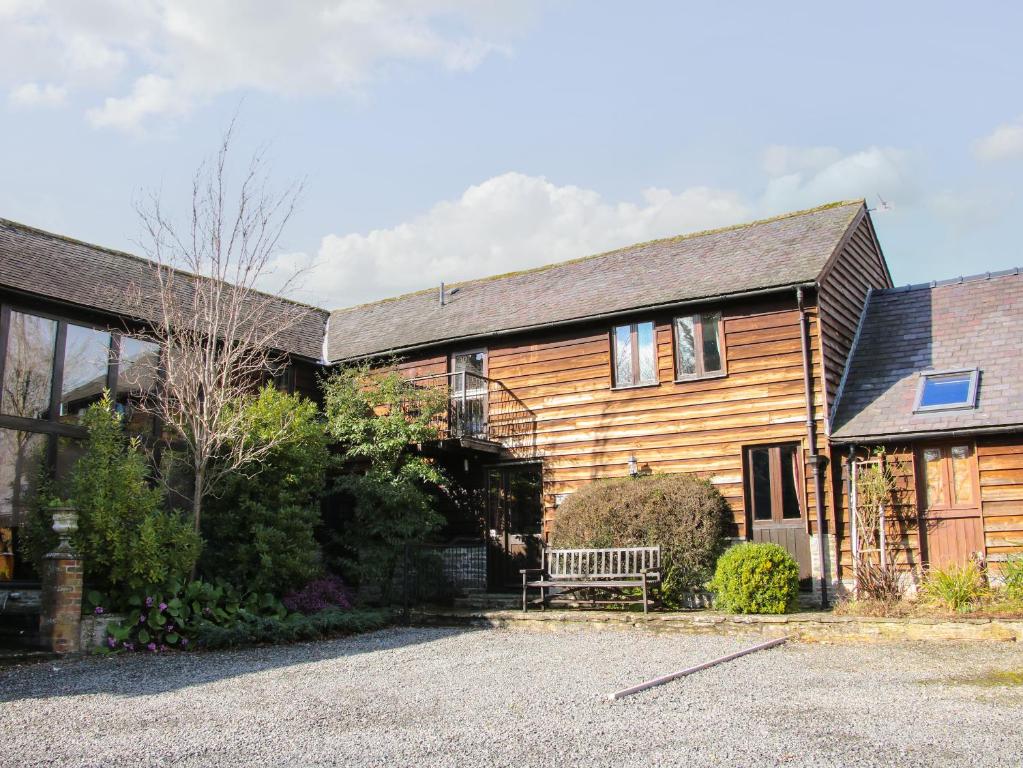 una casa de madera con un banco delante en Swallow Cottage, en Bucknell