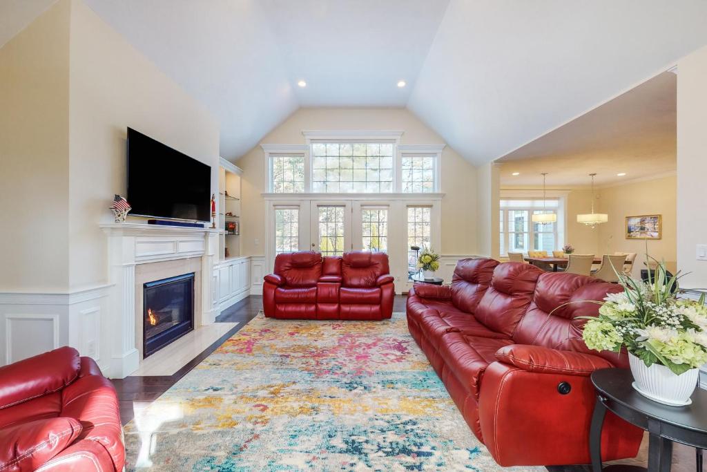 a living room with red leather furniture and a fireplace at Cape Castle in Mashpee
