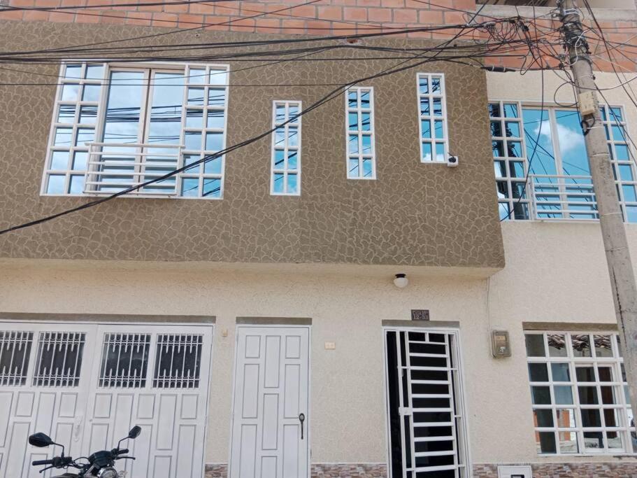 a house with white doors and a bike in front of it at Hospedaje El Cerrito 2 in El Cerrito