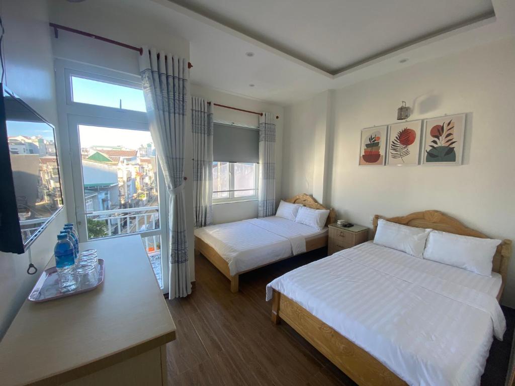 a hotel room with two beds and a window at CSLTDL Minh Hùng in Da Lat