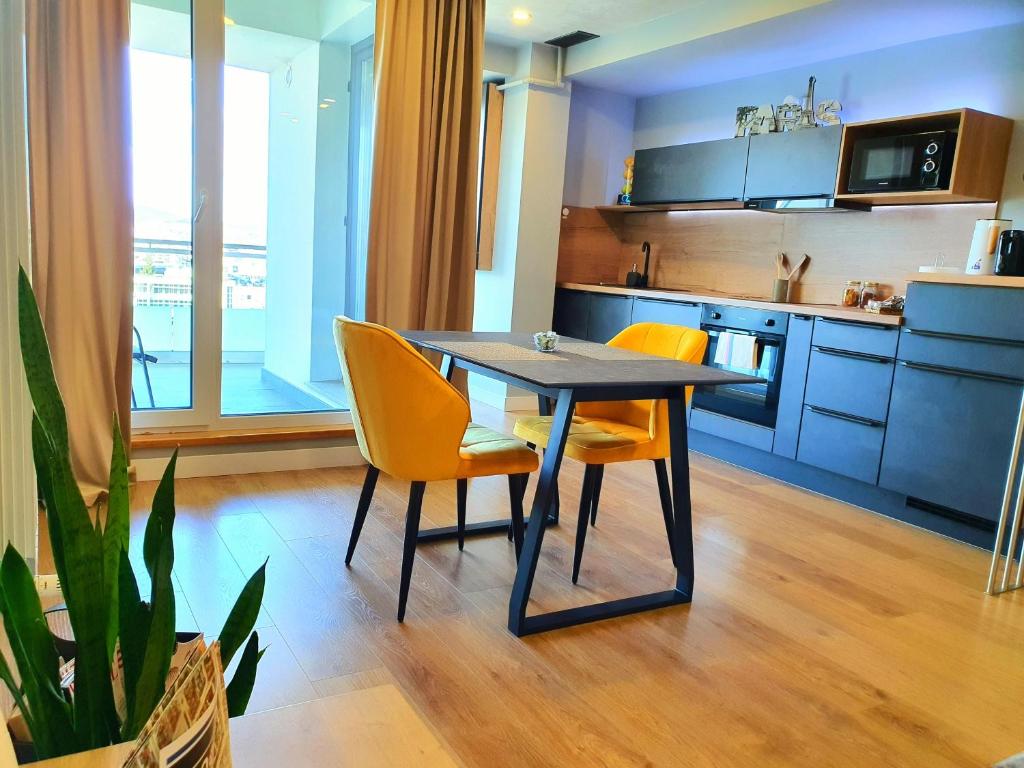 a kitchen with a table and some yellow chairs at Eriss Studio Suite - OZone building apartment in Cluj-Napoca