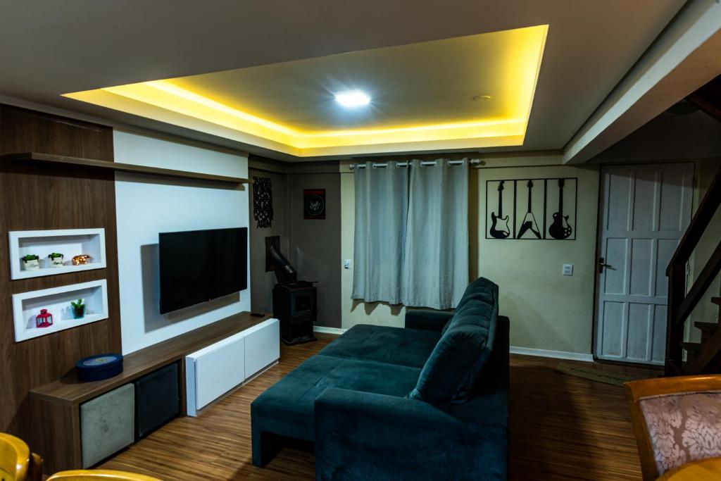 een woonkamer met een blauwe bank en een flatscreen-tv bij Apartamento Completo de 3 quartos em Gramado 2 in Gramado