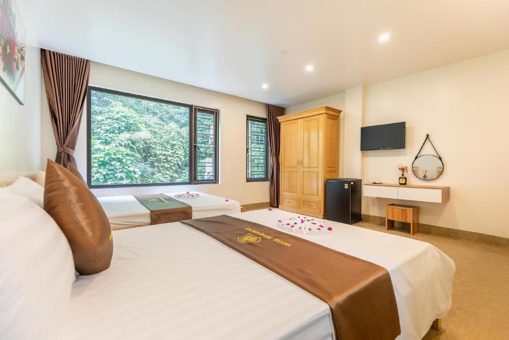 a bedroom with two beds and a large window at Cat Ba Rose Nhung Hotel in Cat Ba