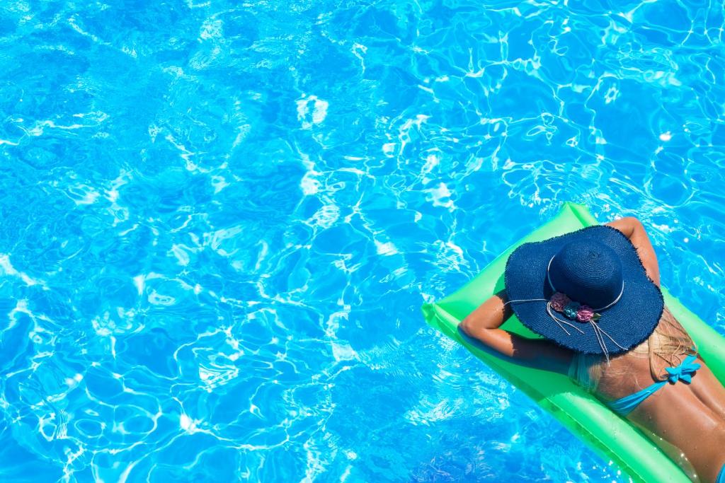 une personne avec un chapeau sur une planche de surf dans une piscine dans l'établissement Mallacoota Hotel Motel, à Mallacoota