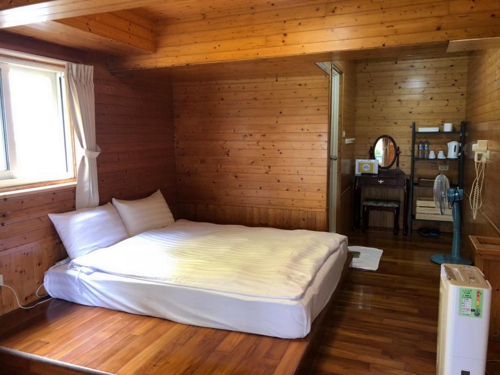 a bedroom with a white bed in a wooden room at Cingjing Brilliant Twins of Seattle in Ren&#39;ai