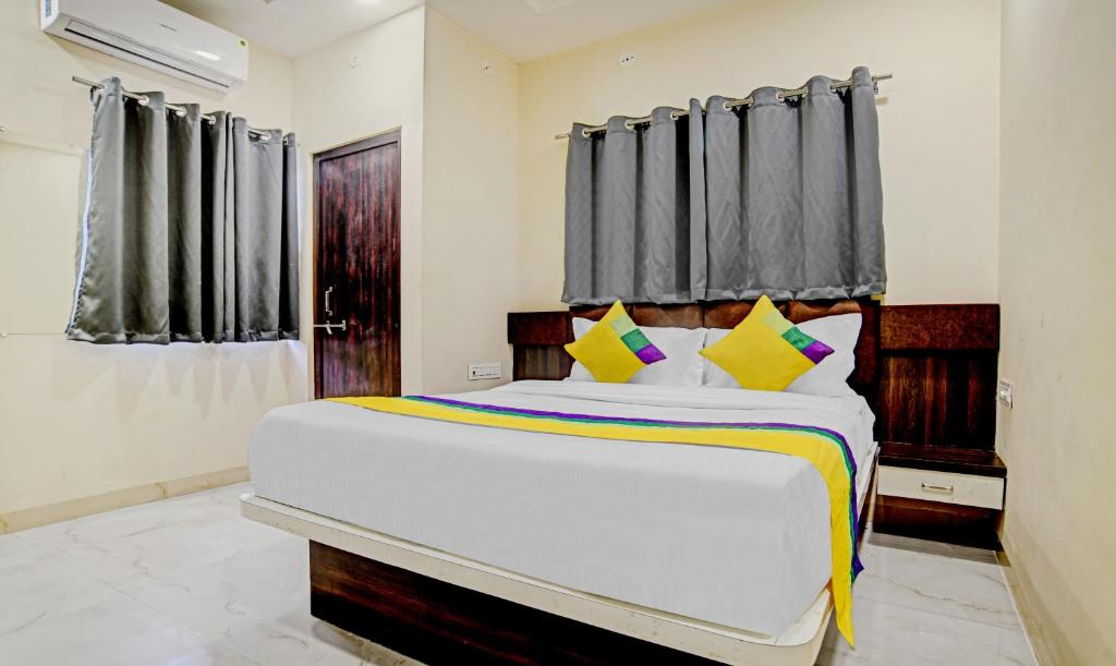 una camera da letto con un grande letto bianco con cuscini gialli di Hotel Anand Shree,Indore a Indore