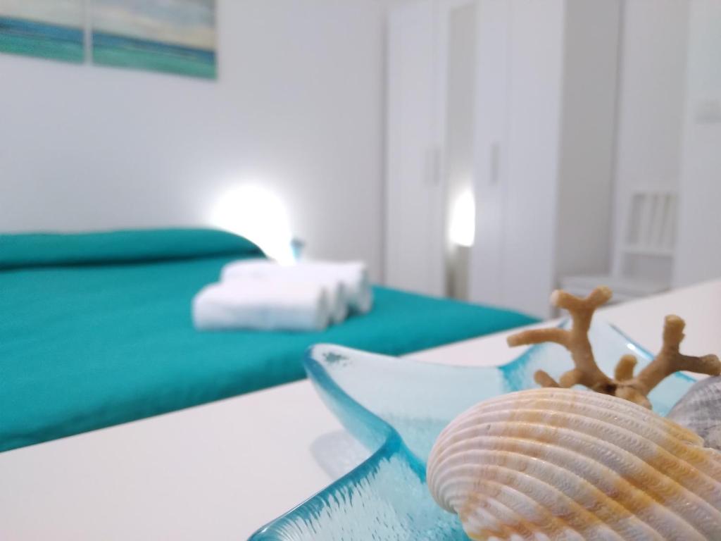 ein Tisch mit zwei Muscheln neben einem Bett in der Unterkunft Casa vacanze Oasis Home PortoPino in Porto Pino