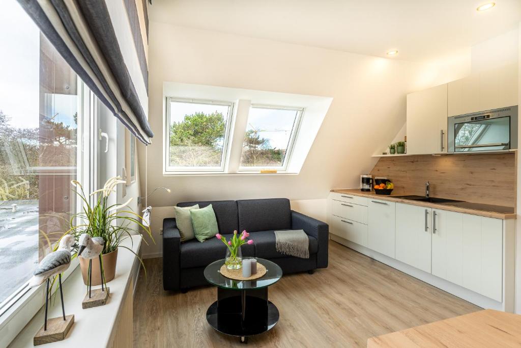 ein Wohnzimmer mit einem Sofa und einem Tisch in der Unterkunft Strandfliederhaus in Norderney