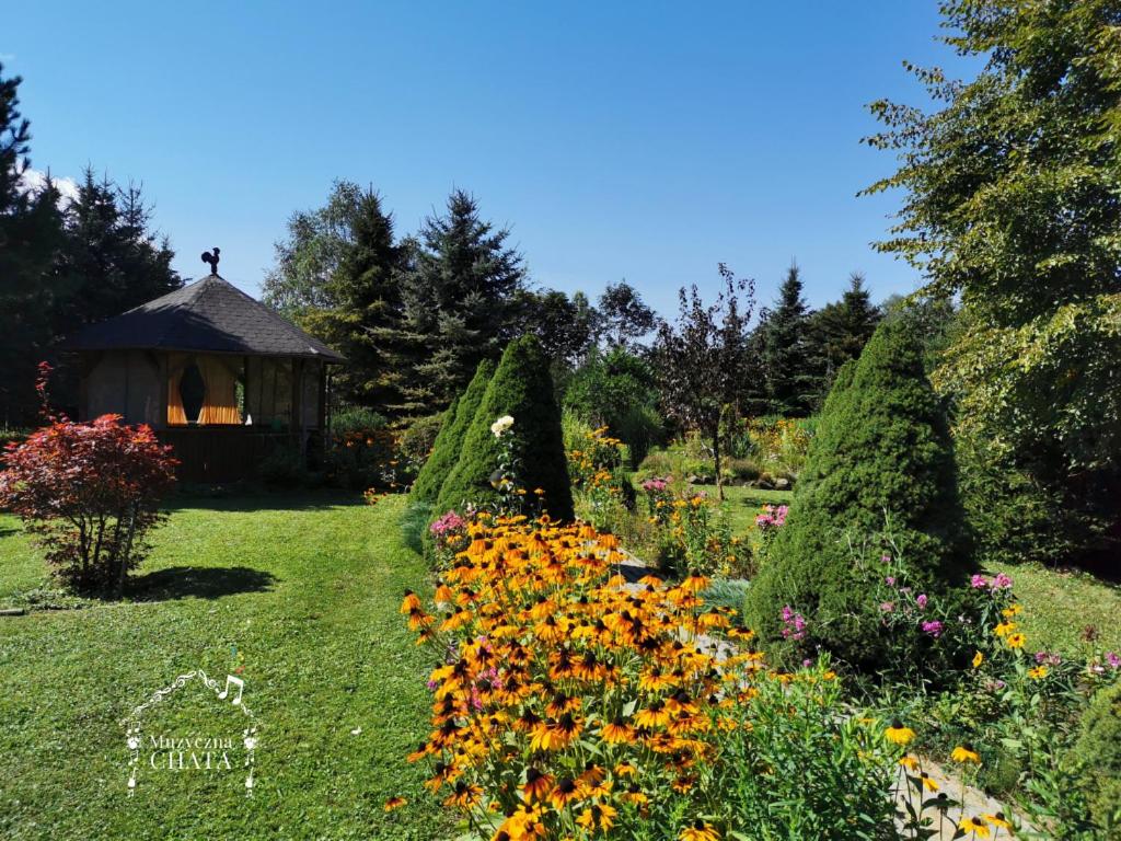 a garden with flowers and a gazebo at Bieszczady Noclegi "Muzyczna Chata" in Olszanica