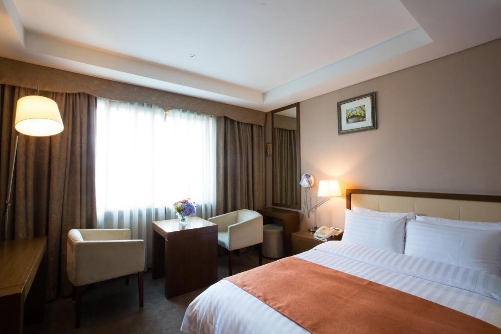 a hotel room with a bed and a desk and a window at Hotel Samjung in Seoul