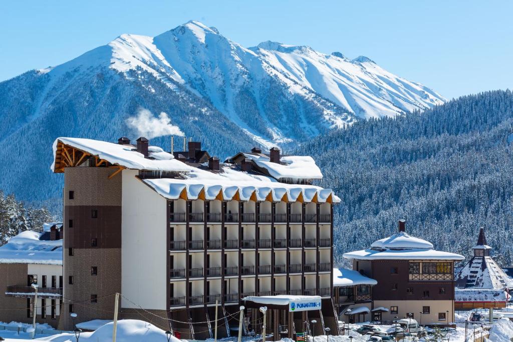 ein Hotel im Schnee mit einem Berg im Hintergrund in der Unterkunft Hotel Complex Romantik in Arkhyz