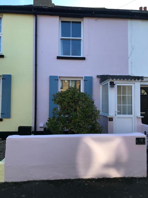 ein weißes Haus mit blauen Fenstern und einem Busch in der Unterkunft Seashell Cottage in Deal