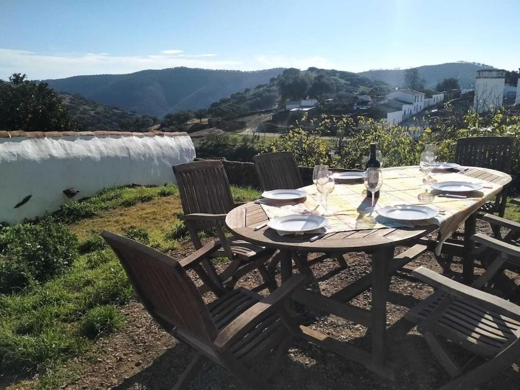 a wooden table with a bottle of wine and glasses at Casa Rural La Caricola in Hinojales