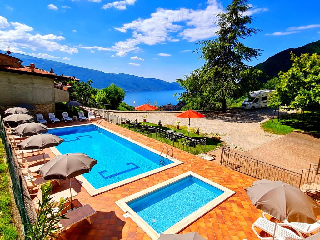 a swimming pool with umbrellas and a view of the water at Residence Casa Silvana in Tignale