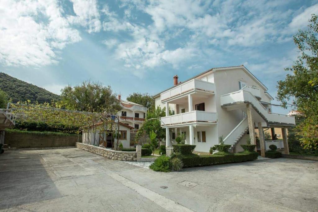 una gran casa blanca con aparcamiento en Apartman Ana en Rab