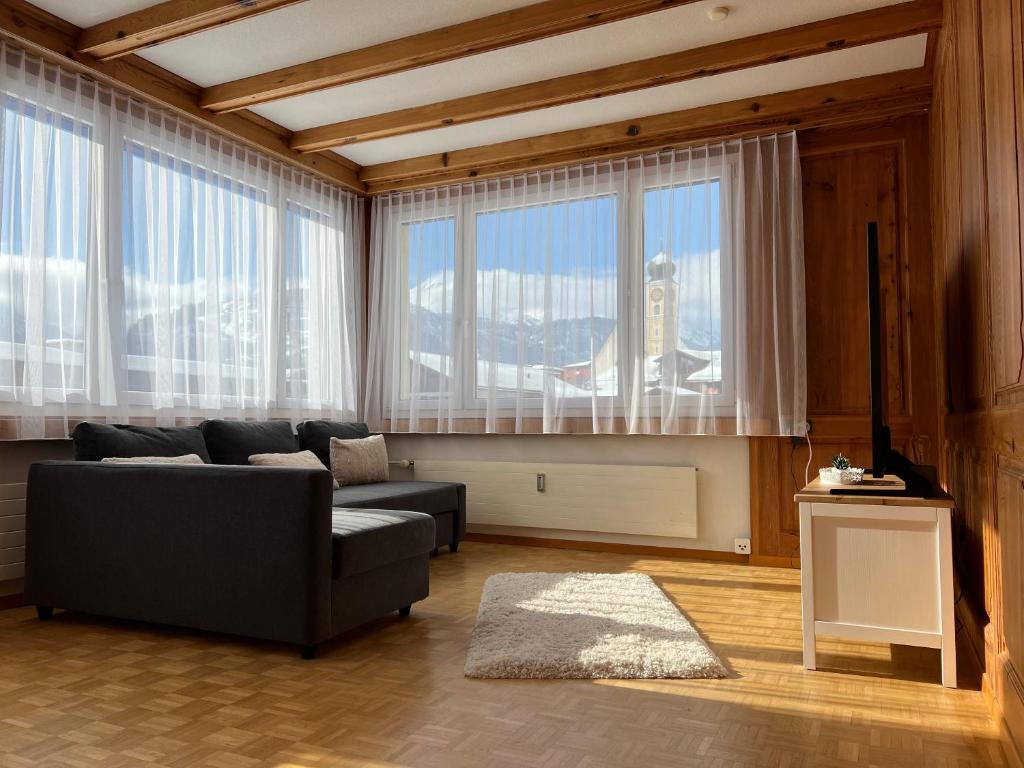 ein Wohnzimmer mit einem Sofa und großen Fenstern in der Unterkunft Ferienwohnung Dorfzentrum in Disentis