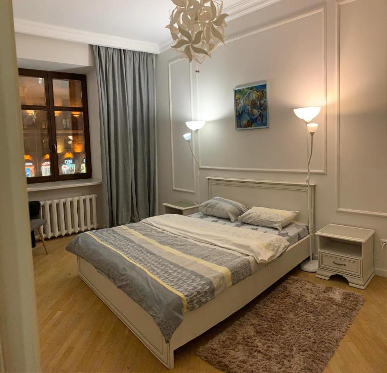 a bedroom with a bed and two lamps and a window at KAZA APART in Minsk