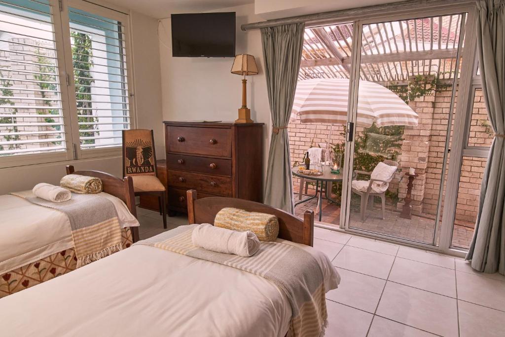 a bedroom with two beds and a view of a patio at Soul Searchers in Jeffreys Bay