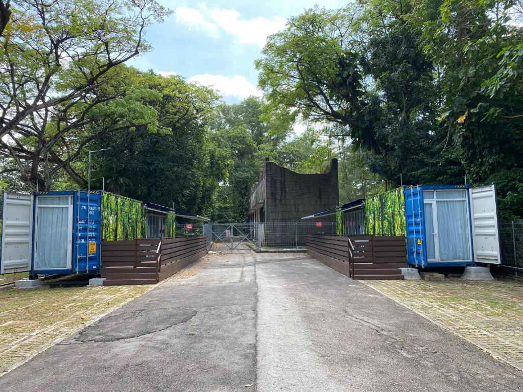a row of gates in a park with trees at Shipping Container Hotel at Haw Par Villa GoogleMap Address 27 Zehnder Road Taxi and cars can only enter via Zehnder Road in Singapore