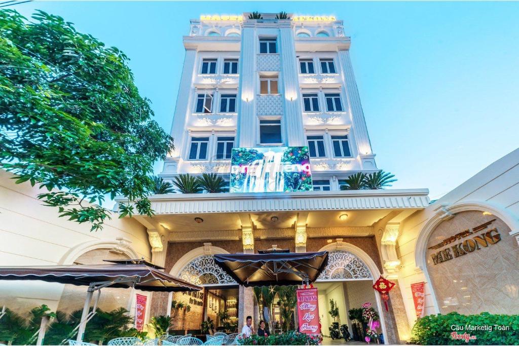 波來古的住宿－Mekong Gia Lai Hotel - Me Kong Pleiku，一座大建筑前面设有桌子和遮阳伞