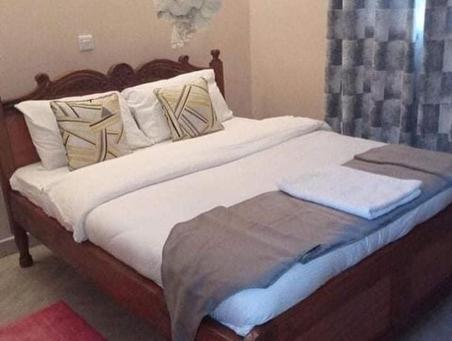 ein Bett mit weißer Bettwäsche und Kissen in einem Schlafzimmer in der Unterkunft Villa Serene Hotel in Kitale