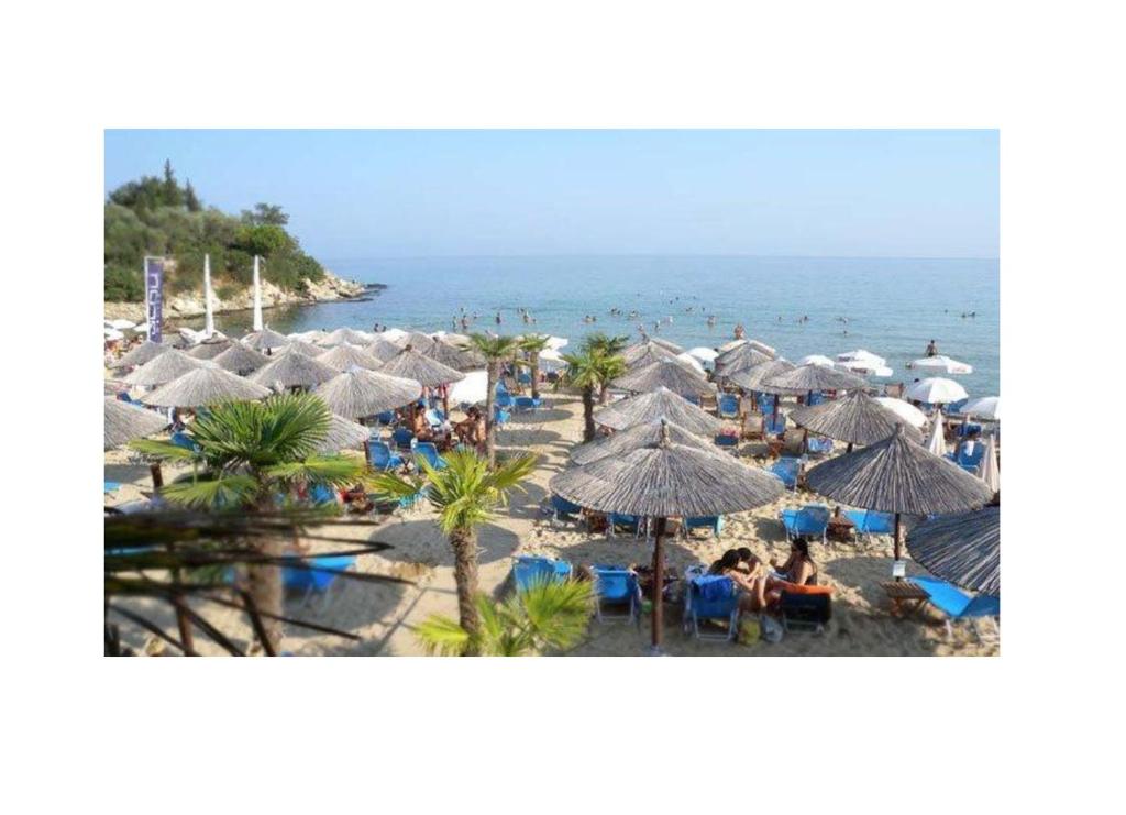 a group of people sitting under umbrellas on a beach at Villa Nickolas in Paleo Tsifliki