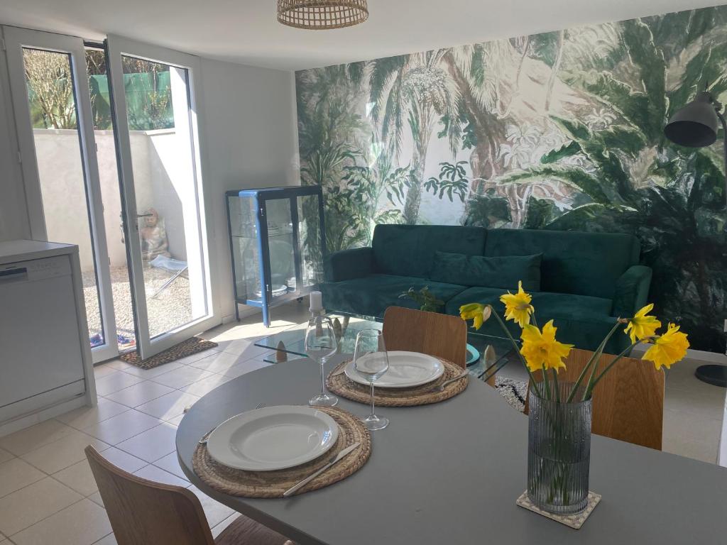 une salle à manger avec une table et un canapé vert dans l'établissement Beldi, Bel appartement dans un environnement calme, à Montgermont